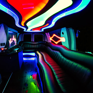 Sprinter Limo Van Interior with black leather seating and colorful mood lighting.