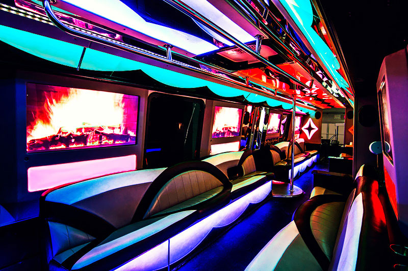 Looking toward the front of the bus, you can see chrome handles on the ceiling and colorful mood lighting throughout.